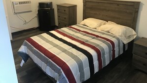 Un dormitorio con una cama, un aparador, un microondas y un equipo de aire acondicionado.