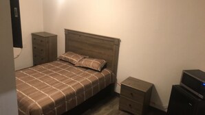Un dormitorio con cama, mesita de noche, cómoda y televisor.