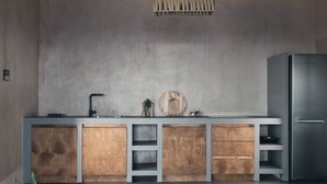 A modern kitchen with a grey countertop, wooden cabinets, and a stainless steel refrigerator. - Vais luxury villas (Zakynthos)