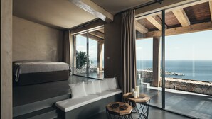A modern bedroom with a bed, a sofa, and two wooden side tables. - Vais luxury villas (Zakynthos)