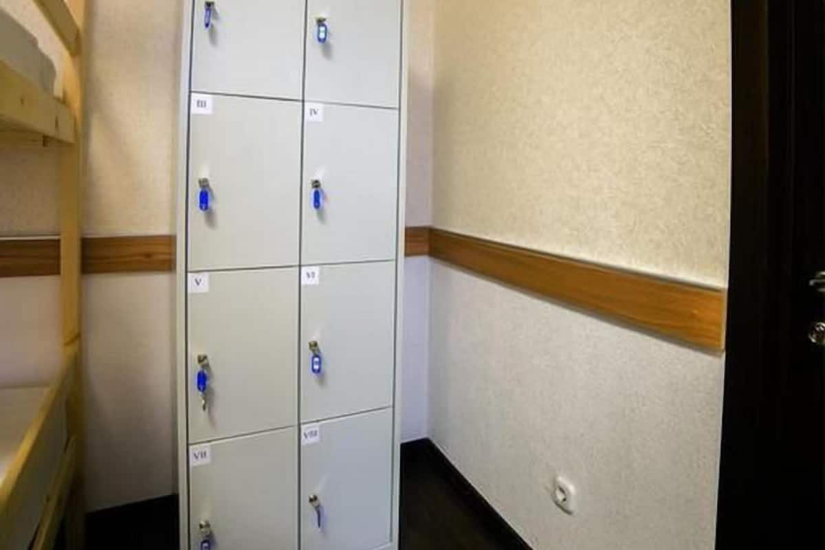 A hallway with a row of metal lockers and a wooden ladder.