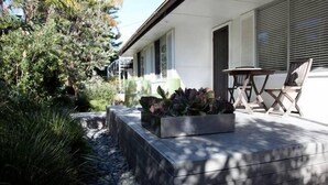 Una casa moderna con un patio, un jardín con plantas y una mesa con sillas.