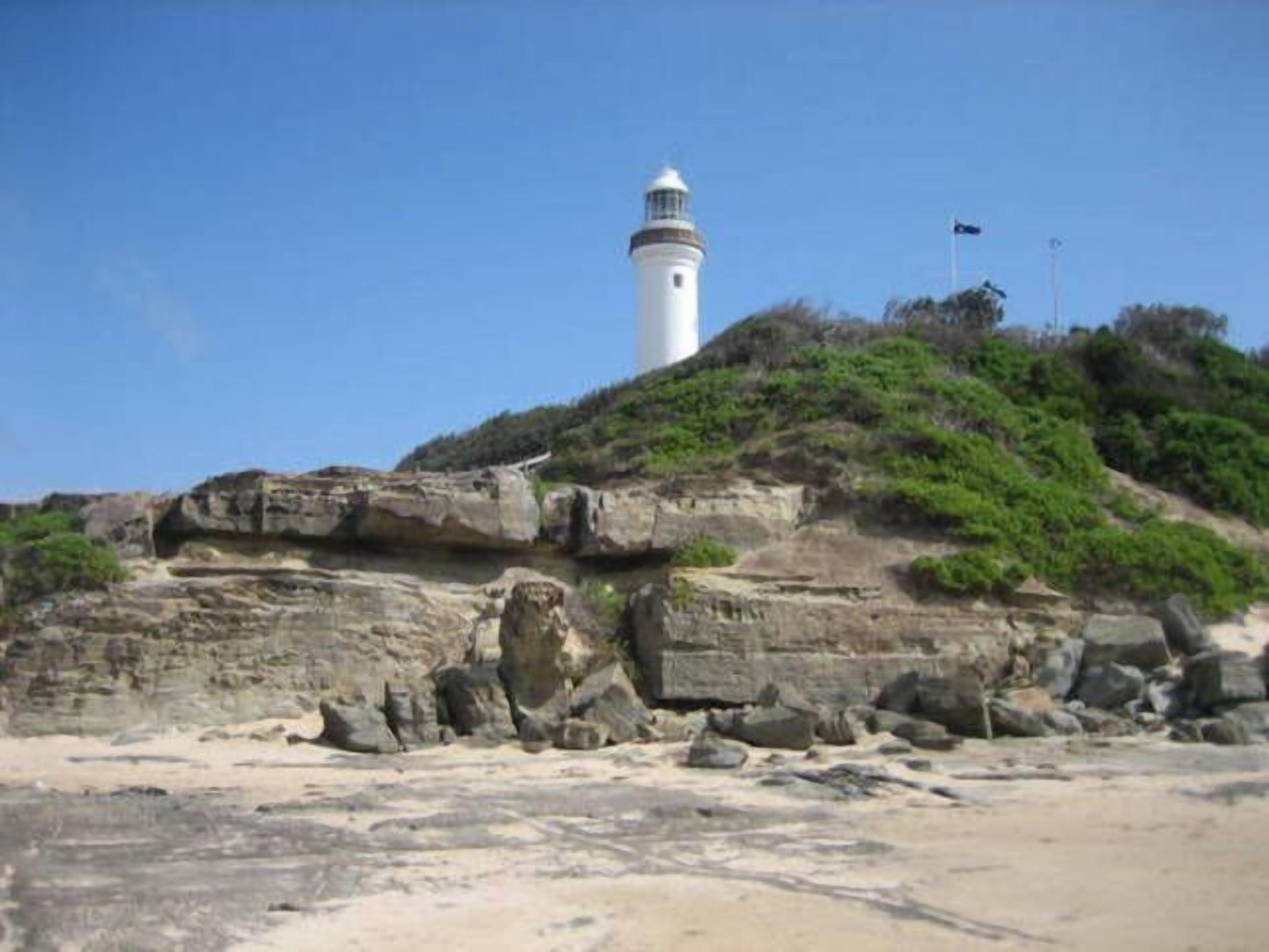 A lighthouse on a rocky cliff with a clear sky.