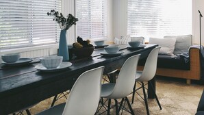 Un comedor con una mesa de madera, sillas blancas y un sofá.