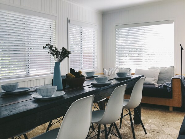 A dining area with a wooden table, white chairs, and a sofa.