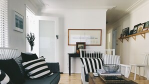 Un salón con un sofá verde oscuro, cojines a rayas, una silla blanca y una mesa de centro con un cuenco.