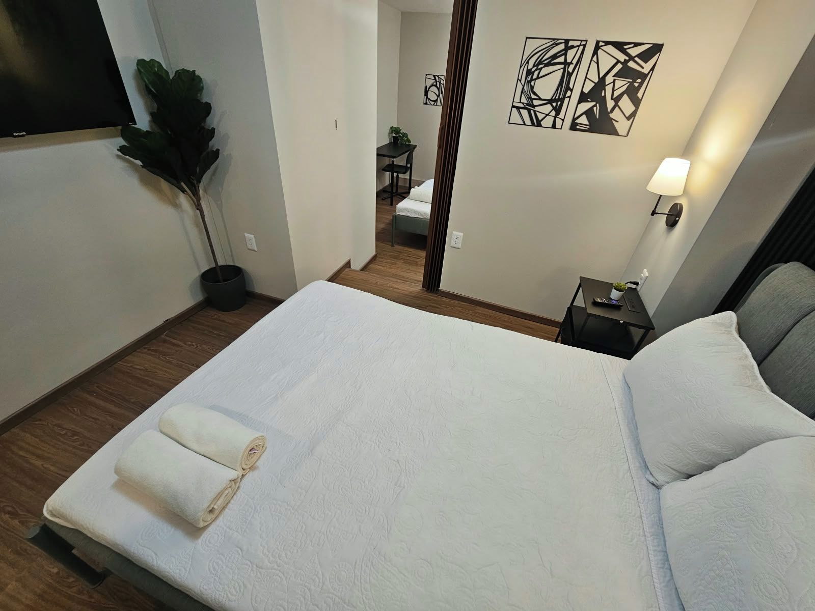 Ein Hotelzimmer mit Bett, Nachttisch, Lampe und einer Zimmerpflanze.