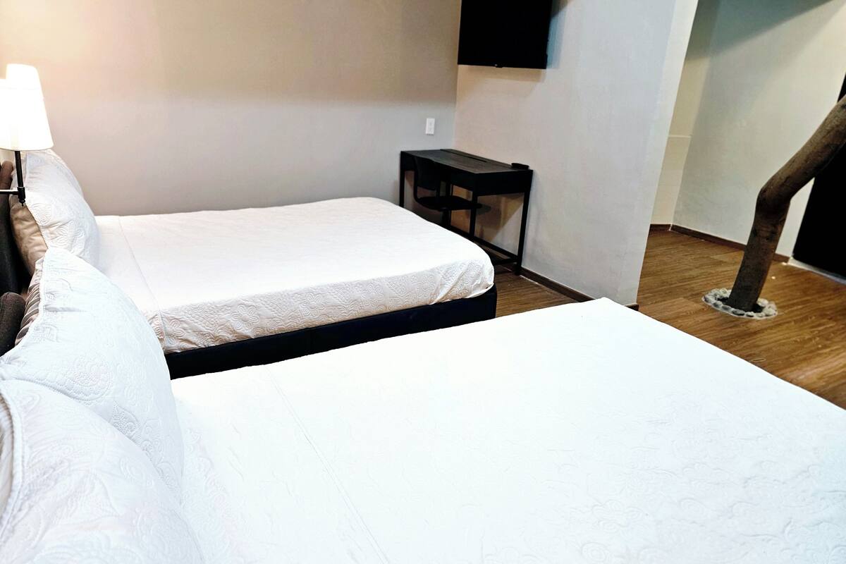 A hotel room with two beds, a TV mounted on the wall, and a small table.