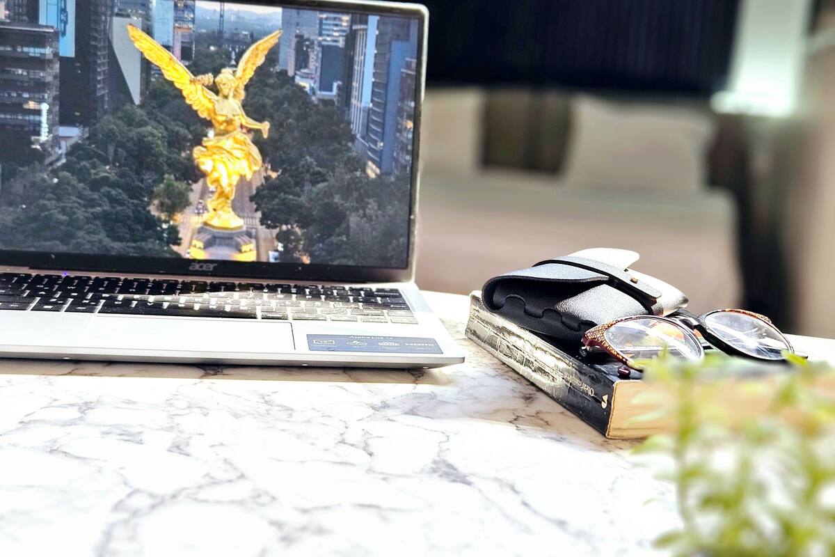 A laptop displaying a golden statue, a pair of glasses, and a book on a marble surface.