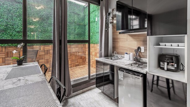 A modern kitchen with a large window, a built-in oven, and a coffee machine. - Singular Goldsmith (Mexico City)