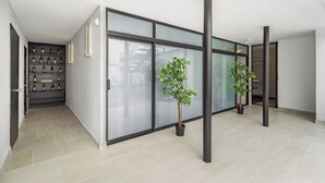 A modern hallway with a glass partition, potted plants, and a wine rack. - Singular Goldsmith (Mexico City)