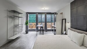 A modern bedroom with a large bed, a desk, and a balcony with a view. - Singular Goldsmith (Mexico City)