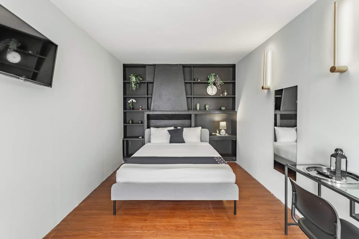 A modern bedroom with a bed, bedside tables, a desk, and built-in shelving.