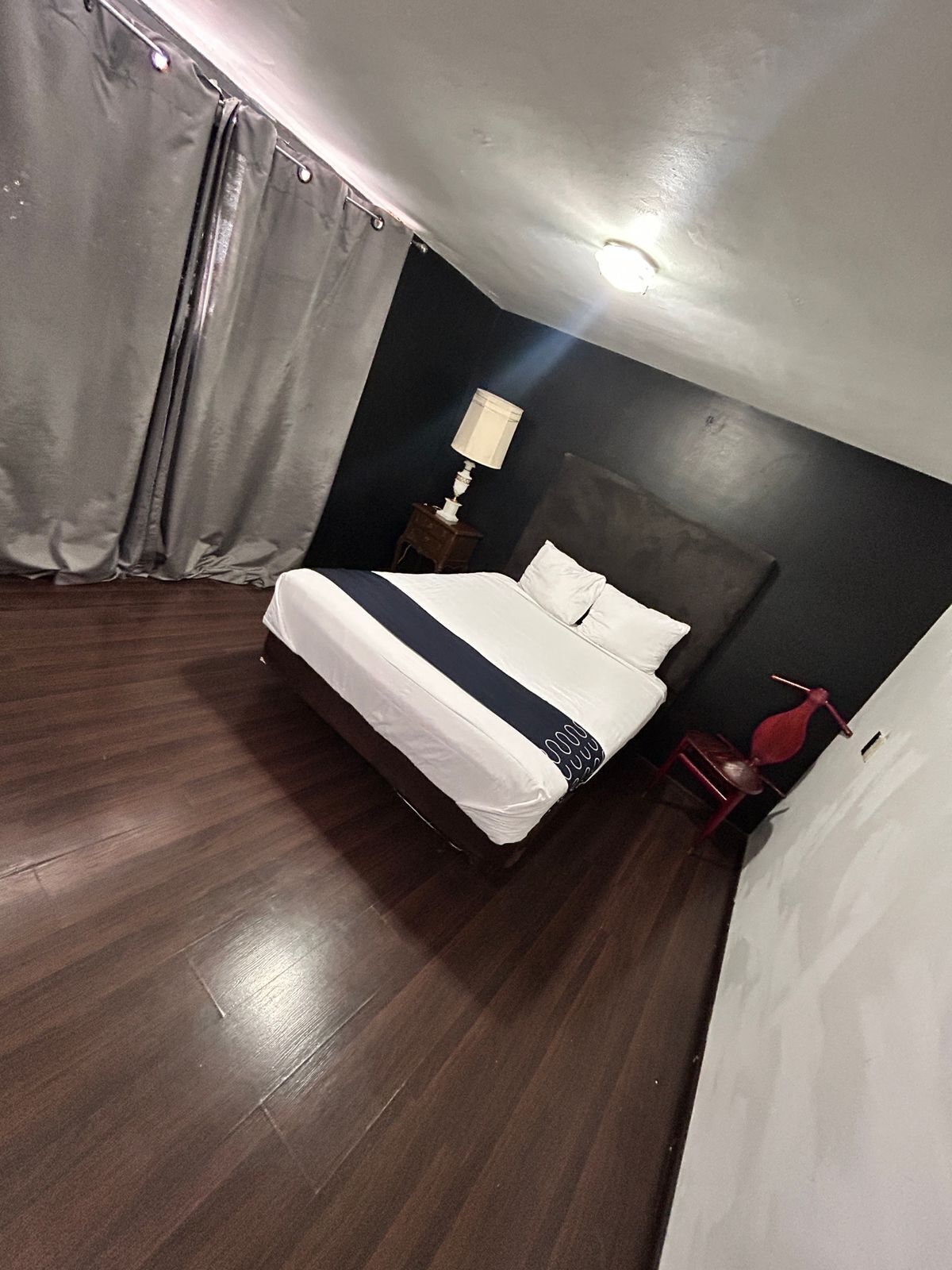 A bedroom with a bed, a nightstand, a lamp, and a red chair.