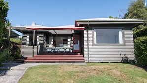 A single-story house with a front porch, a small attached garage, and a large window on the right side. - Absolute lakefront holiday house (Two Mile Bay (2 Mile Bay))
