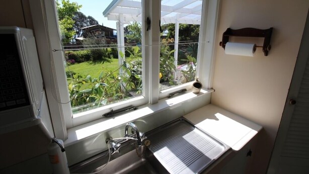 A kitchen with a window, sink, and a view of greenery outside.