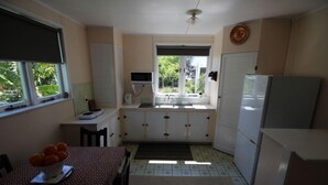 A compact kitchen with a dining area, a microwave, a refrigerator, and a window with a view of greenery.