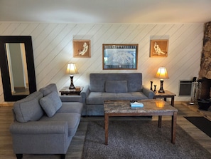 A living room with a sectional sofa, two side tables with lamps, a coffee table, and framed artwork on the wall.
