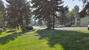 A residential street with houses, parked cars, and a grassy area with trees. - Snowcreek Resort Vacation Rental 201 (Mammoth Lakes)
