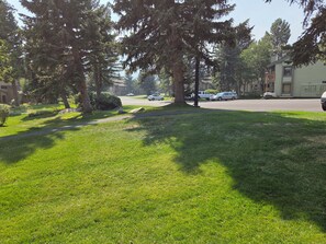 A residential street with houses, parked cars, and a grassy area with trees. - Snowcreek Resort Vacation Rental 201 (Mammoth Lakes)