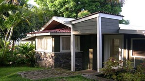 Uma casa com base de pedra, varanda coberta e telhado vermelho.