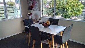 Un comedor con mesa y sillas, un cuenco de fruta y un cuadro en la pared.