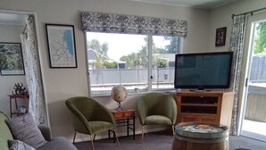 Un salón con sofá, dos sillones, un globo terráqueo, televisor y una mesa de centro de caoba.