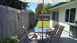 Una terraza con una mesa, sillas, una sombrilla y una valla de madera.