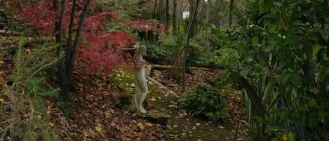 A garden with a statue, surrounded by trees and foliage.