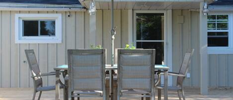 A patio with a table and chairs, an umbrella, and a water spigot.