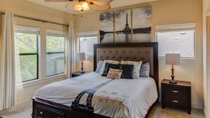 A bedroom with a large bed, a ceiling fan, and a view of the Eiffel Tower through the window. - Whole Home Air Cleaner, Quiet surroundings, deck and Jacuzzi, near golf course (Austin)