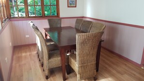 Un comedor con una mesa de madera oscura y sillas de mimbre.