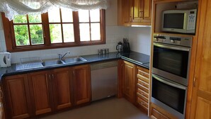 Una cocina con gabinetes de madera, lavavajillas, microondas y horno.