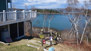 A lakeside property with a deck, a caution sign, and a view of the lake. - Breathtaking Remote Oceanfront Oasis Panoramic Clifftop Views (Lubec)