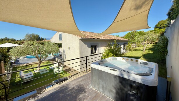 A hot tub on a patio with a house in the background. - Comfortable villa with heated pool and spa between sea and mountains (Aléria)