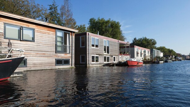 Una casa flotante con un muelle, un bote y un río.