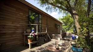 Una cabaña de madera con terraza, asientos exteriores y plantas en macetas.