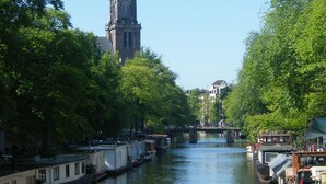 Un canal con barcos, una torre del reloj y árboles a lo largo del agua.