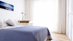 Un dormitorio moderno con una cama grande, suelo de madera y vistas al exterior.