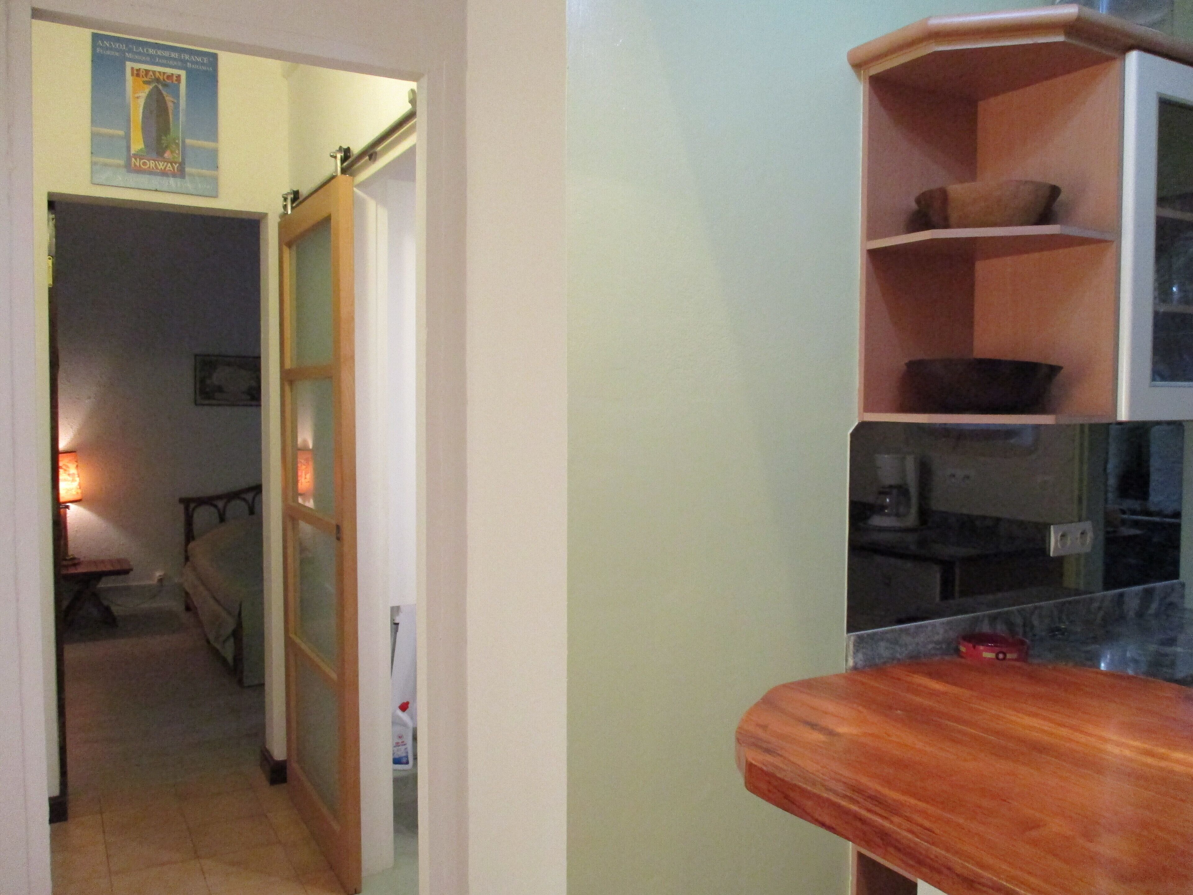 A kitchen with a wooden countertop, a microwave, and a shelf with a bowl.