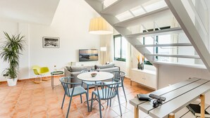 A modern living room with a round table, blue chairs, a sofa, a TV, and a staircase with a view. - Begur Sunset ,2 bedroom loft close to the center of Begur. With terrace and gorgeous sea views (H42) (Begur)