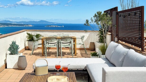 A terrace with a wooden table, two lounge chairs, a sofa, and a view of the sea. - Begur Sunset ,2 bedroom loft close to the center of Begur. With terrace and gorgeous sea views (H42) (Begur)