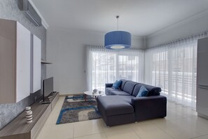 A modern living room with a sofa, a coffee table, and a TV.