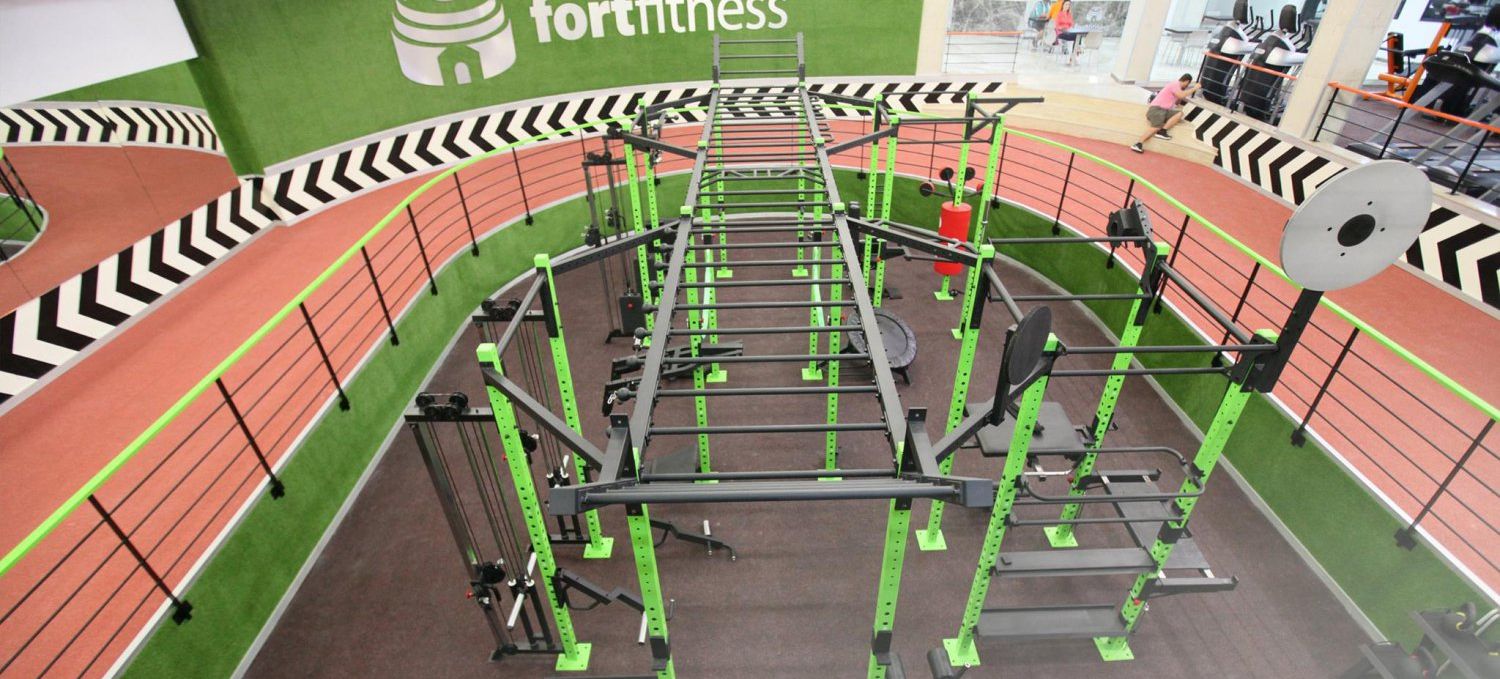 A gym with a running track, weightlifting equipment, and a green wall with the word 'fortiss'.