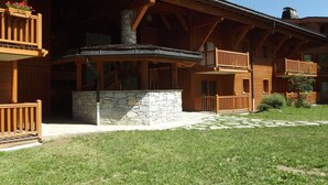 Eine Holzhütte mit Kamin aus Stein, Balkonen und einer Steinwand.
