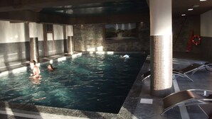 Ein Innenpool mit klarem Wasser, Steinwänden und einer gefliesten Säule.