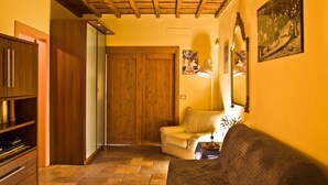 Un salon chaleureux avec un plafond en bois, un canapé, un fauteuil et un téléviseur.
