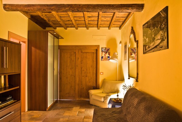 A cozy living room with a wooden ceiling, a sofa, a chair, and a television.