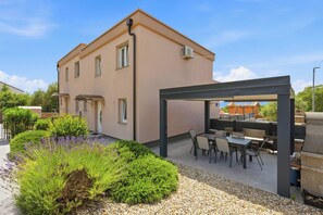 A two-story building with a patio area featuring outdoor seating and a barbecue grill.