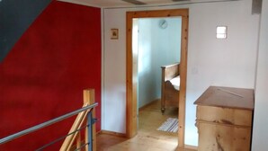 A room with a red wall, a wooden door, a small clock, and a wooden cabinet. - Franconian half-timbered house for 5 people (Krombach)
